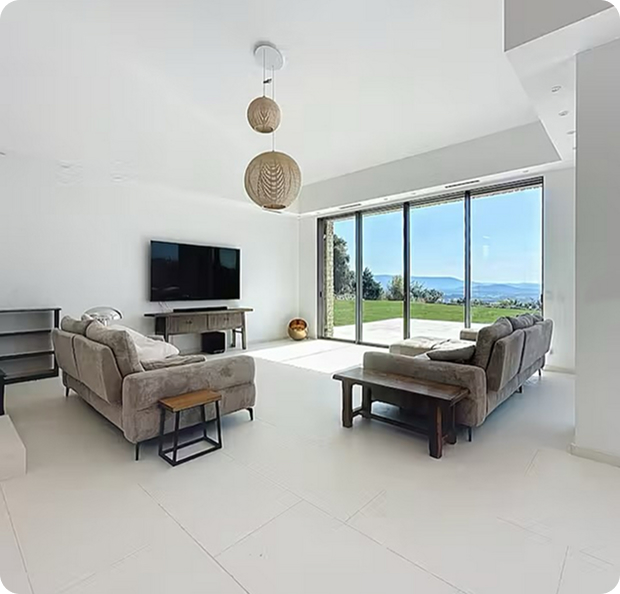 Salon moderne lumineux avec canapés, TV et grandes baies vitrées donnant sur un paysage verdoyant. à Saint-Nazaire-de-Pezan près de Montpellier dans l'Hérault 34