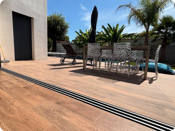 Terrasse extérieure en bois avec table, chaises, transat et parasol, bordant une piscine à Saint-Nazaire-de-Pezan près de Montpellier dans l'Hérault 34