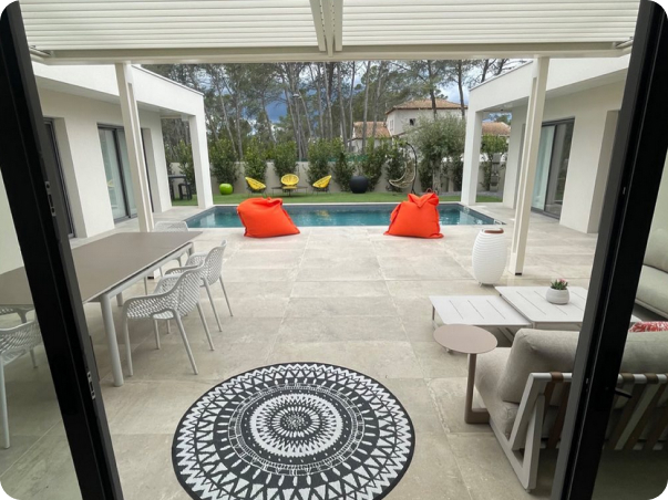 Piscine extérieure moderne avec coin repas, salon, poufs orange et tapis circulaire à Saint-Nazaire-de-Pezan près de Montpellier dans l'Hérault 34