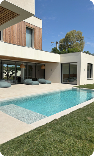 Maison moderne avec piscine, pelouse et arbres sous un ciel bleu à Saint-Nazaire-de-Pezan près de Montpellier dans l'Hérault 34