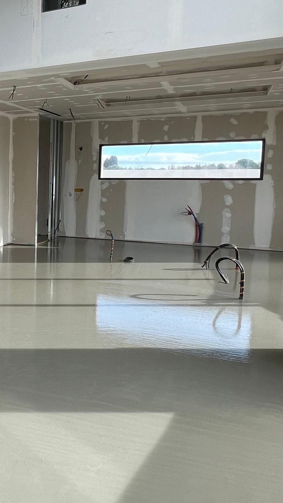 chape fluide, Intérieur d'une construction inachevée avec fenêtres panoramiques, fils électriques, et sol réfléchissant à Saint Nazaire de Pézan près de Montpellier dans l'Hérault 34